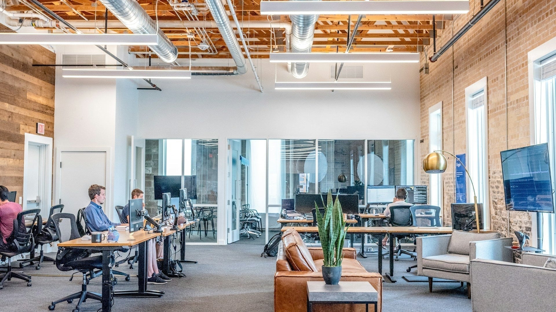 Modern open office with employees working at desks and lounge area, reflecting collaboration and 4-day work week productivity benefits.