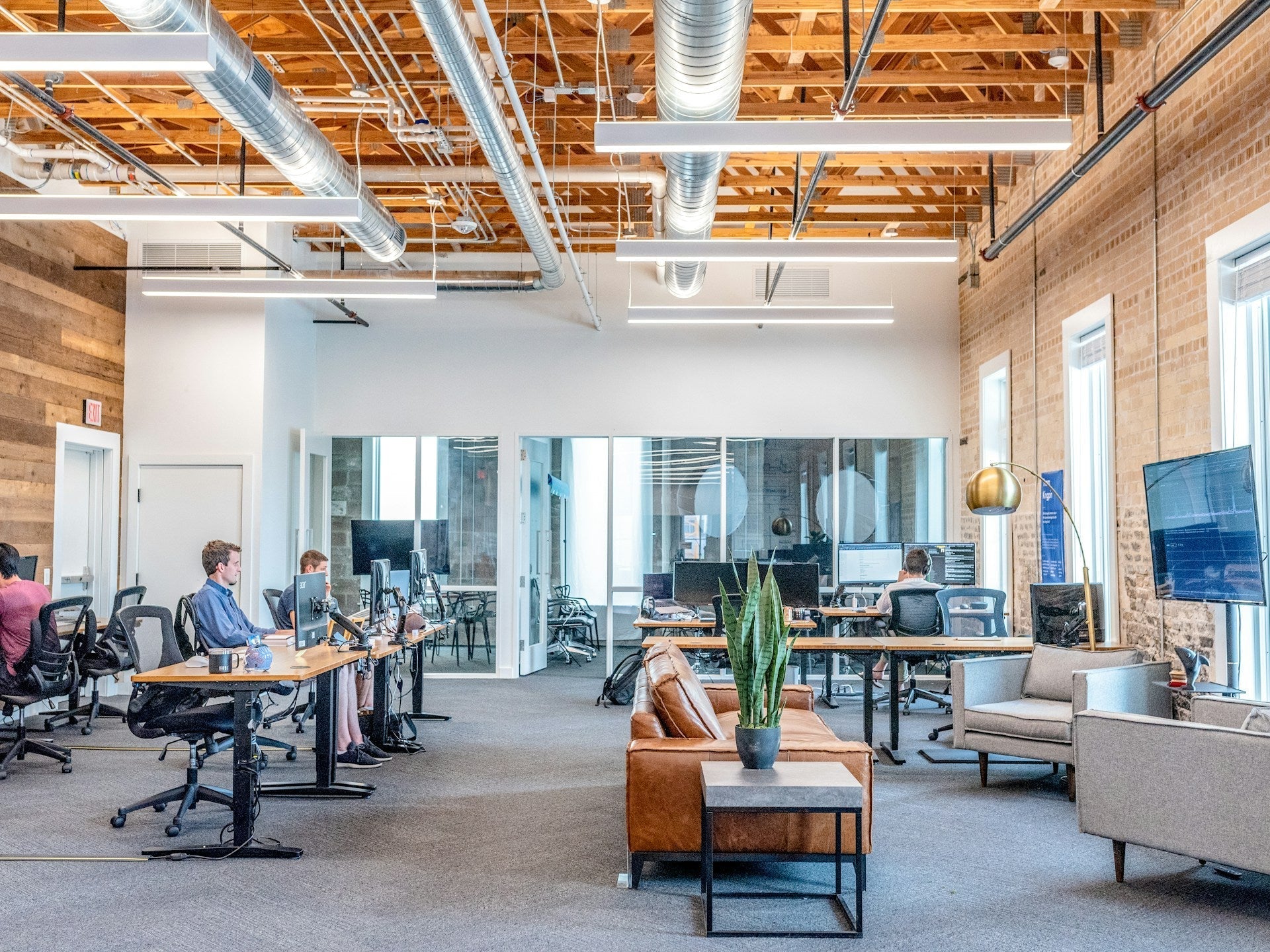 Modern open office with employees working at desks and lounge area, reflecting collaboration and 4-day work week productivity benefits.