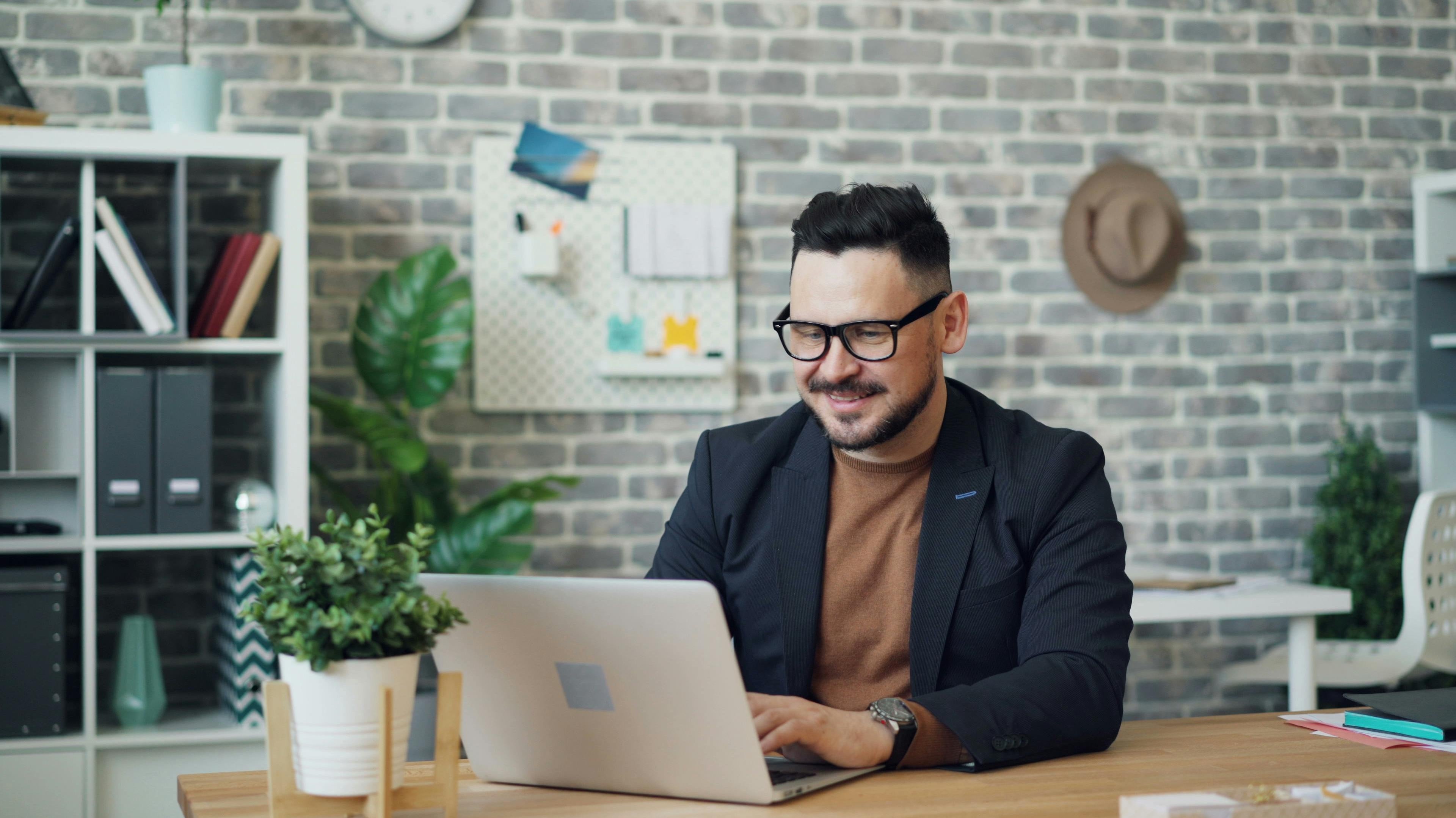 A Man Using a Laptop while Sitting at a Desk in an Office