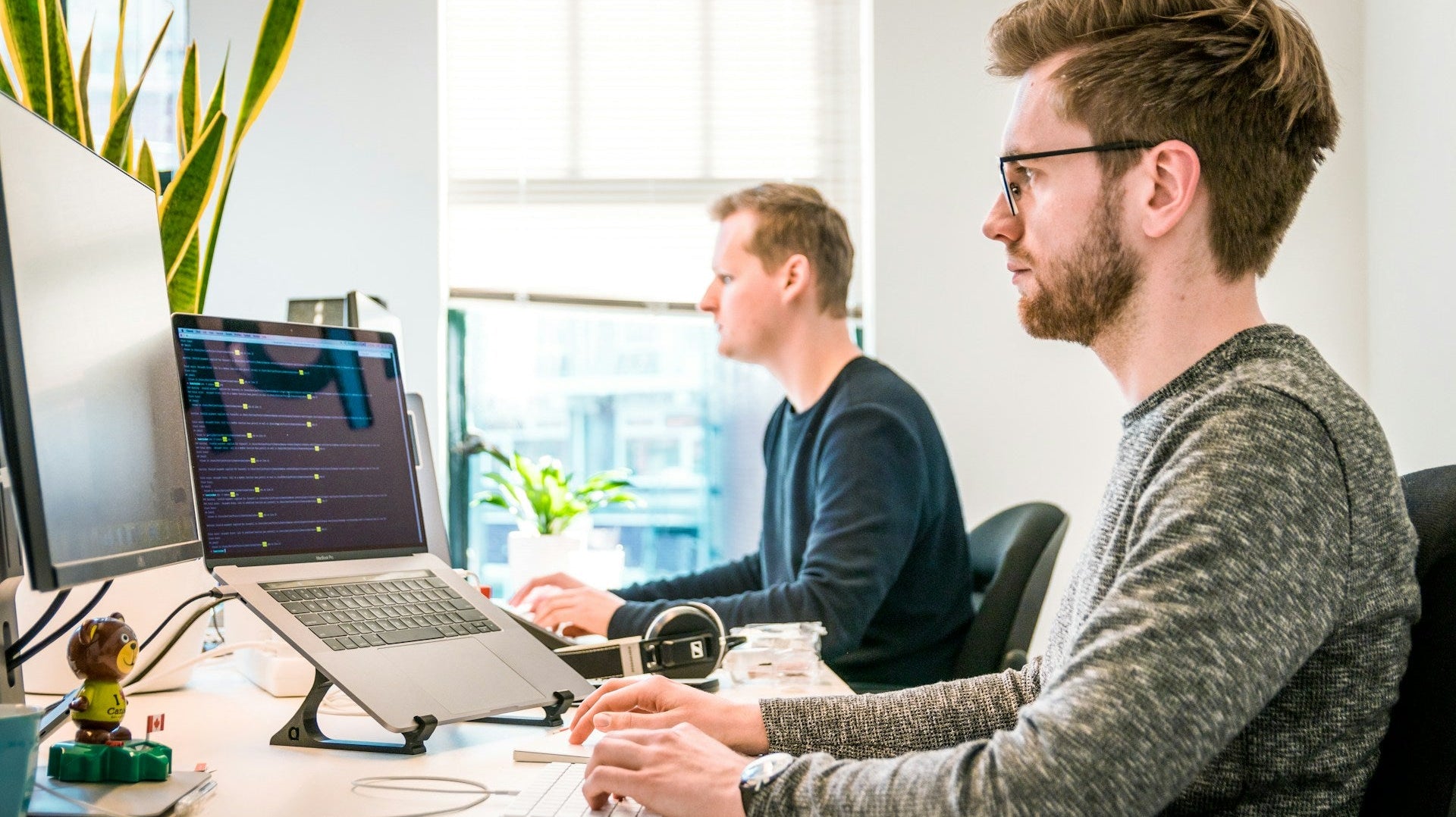 Two professionals working on computers in a bright office setup designed to enhance work productivity and focus. Photo by Tim van der Kuip on Unsplash