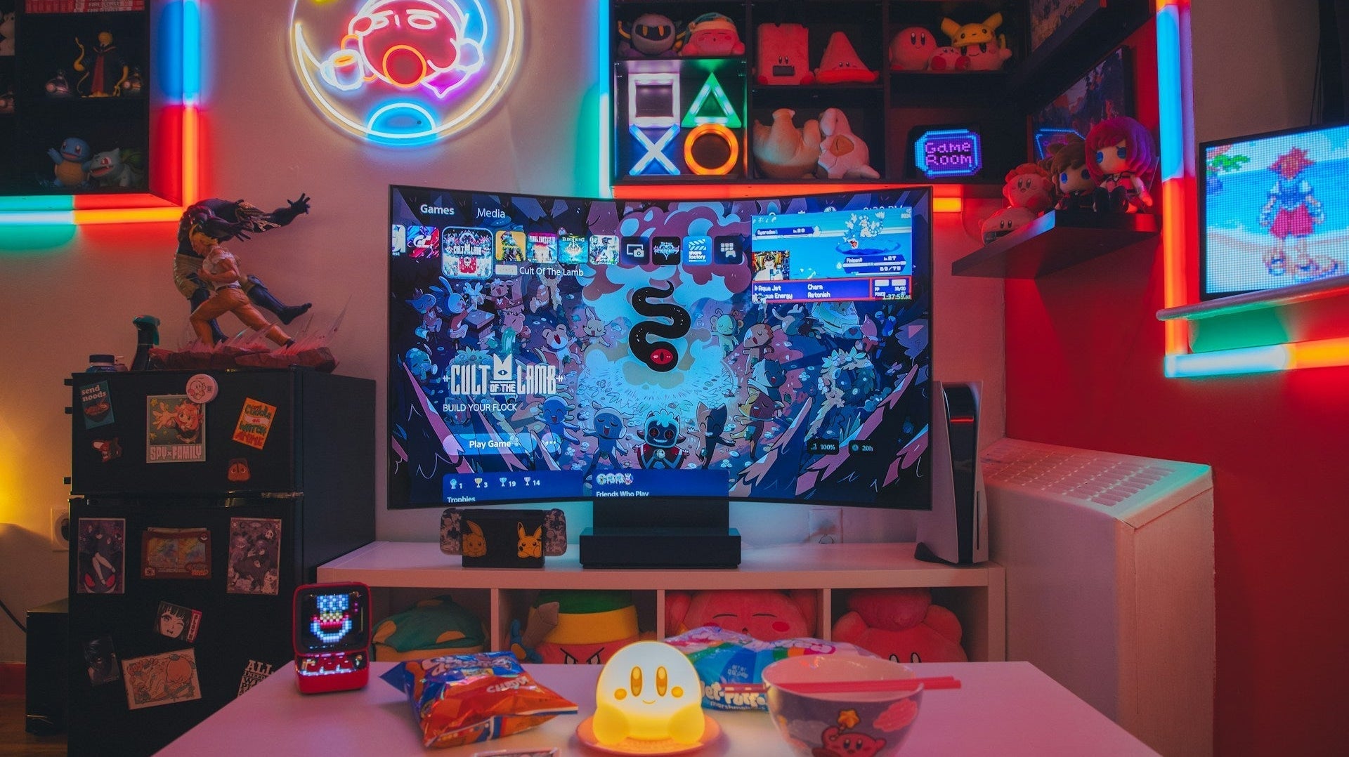 Colorful gaming room with LED lights, a large TV displaying a game, snacks on a table, and neon signs on the walls.