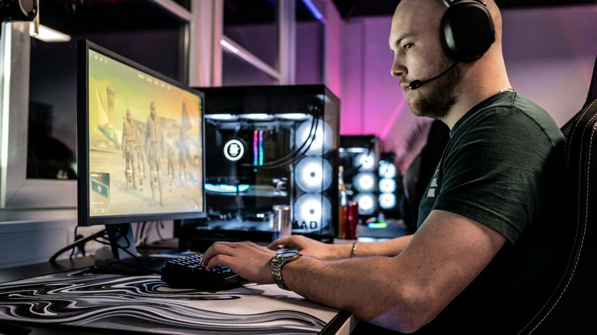 gaming room setup ideas. man playing a PC game in a well lit gaming room. photo by Ella Don via Unsplash