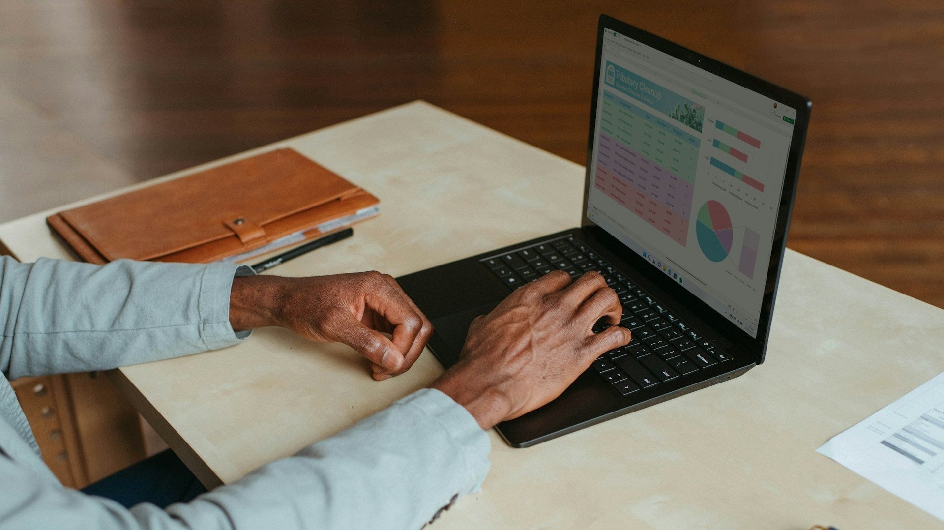 Person working on laptop with charts, representing jobs that your work from home full time in a modern office setup. Image by Windows via www.unsplash.com