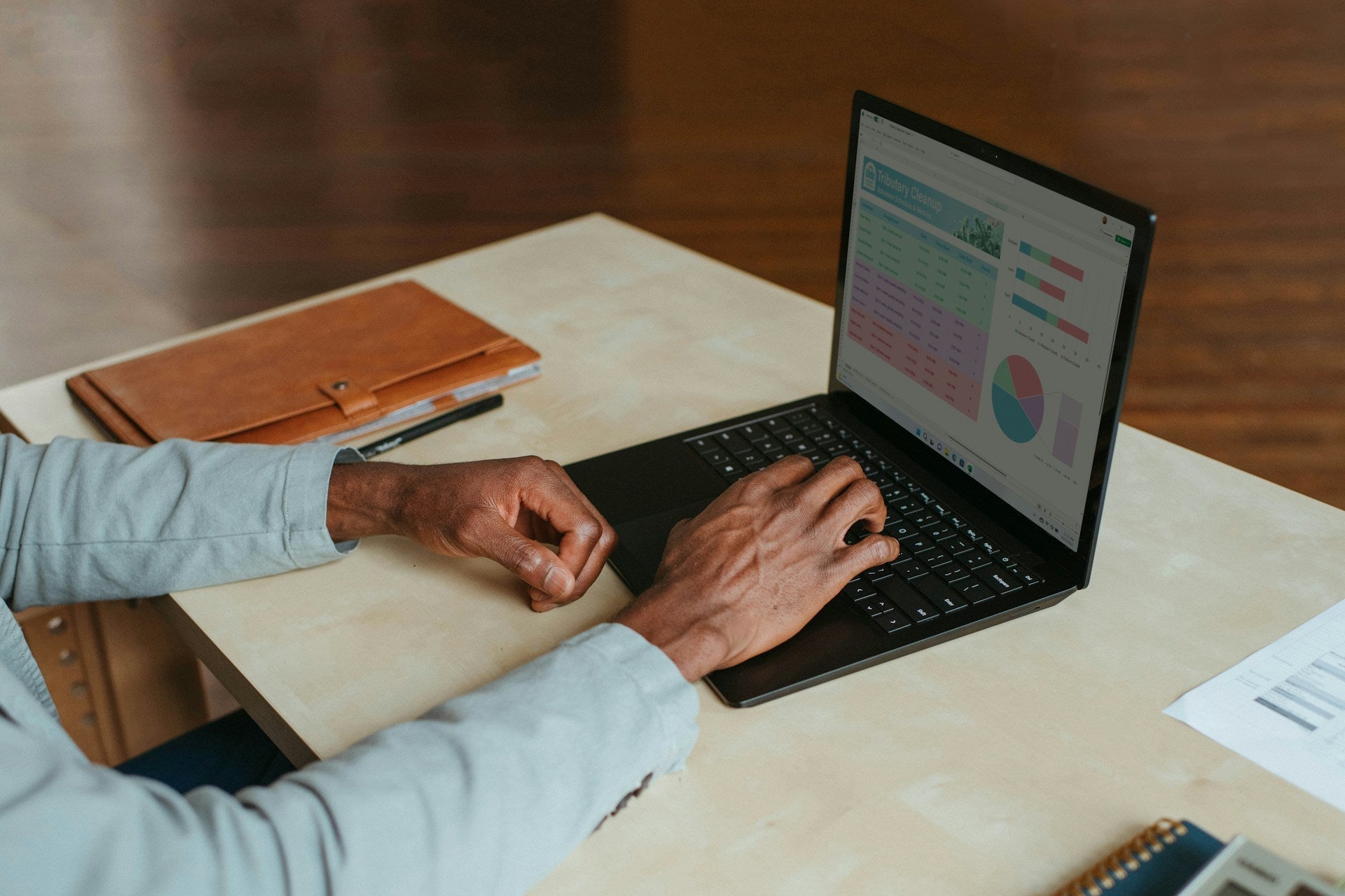 Person working on laptop with charts, representing jobs that your work from home full time in a modern office setup. Image by Windows via www.unsplash.com