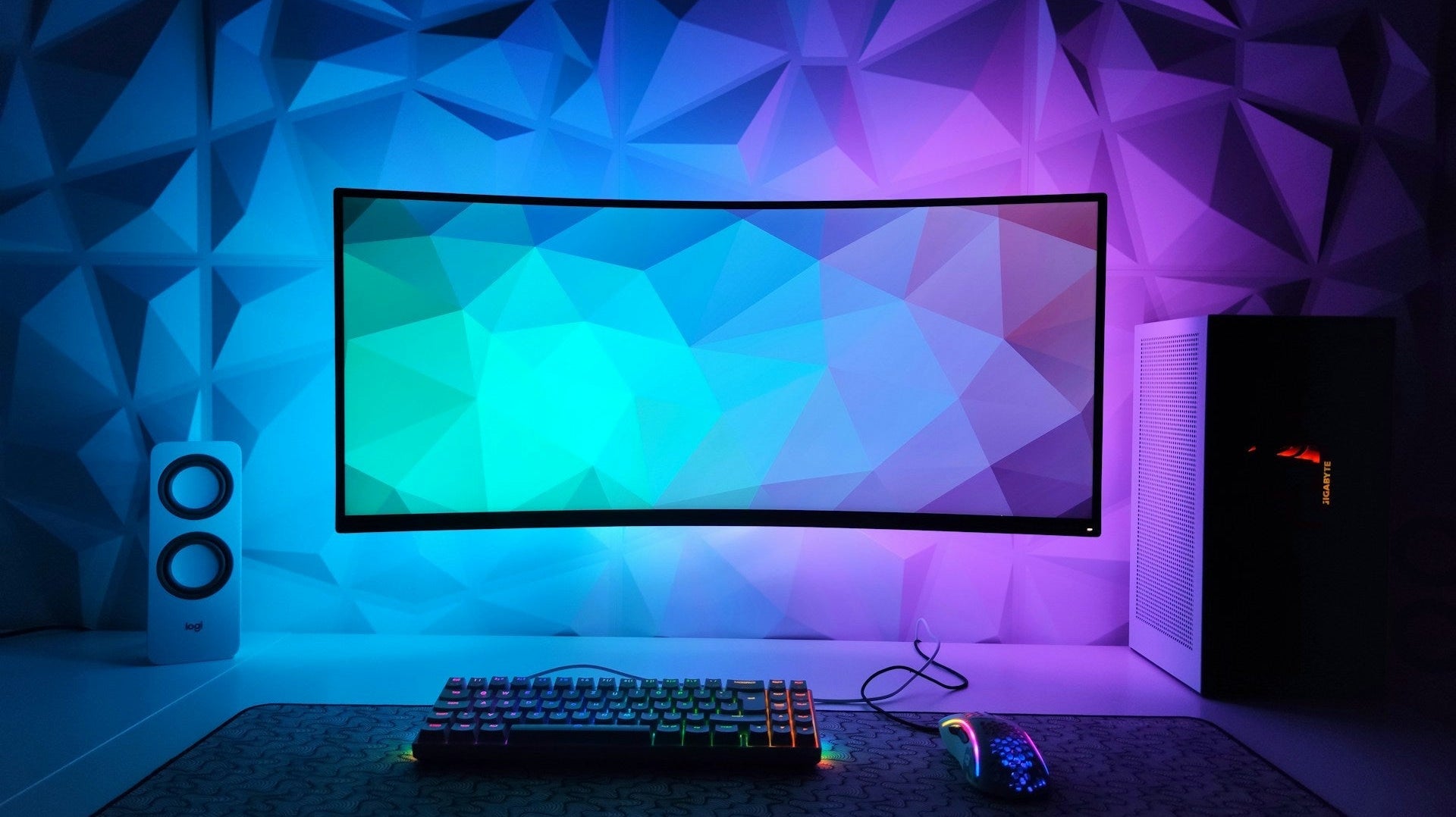 A clean and modern gaming desk with RGB-lit keyboard and mouse, featuring a curved monitor and ambient lighting-perfect for those seeking simple gaming setup ideas.