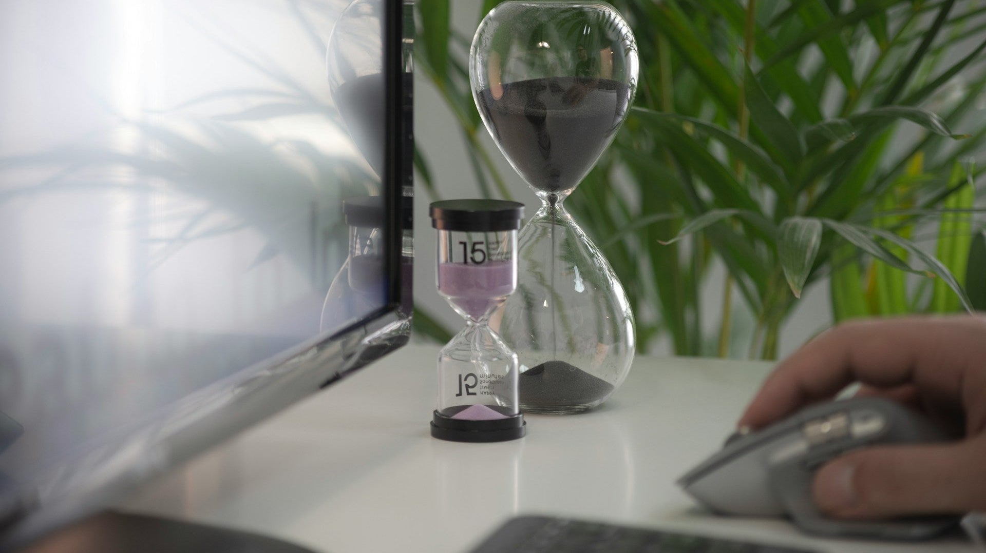 work success means time management. two hourglasses placed beside a monitor while a person is working the mouse. Image by Milad Fakurian via www.unsplash.com
