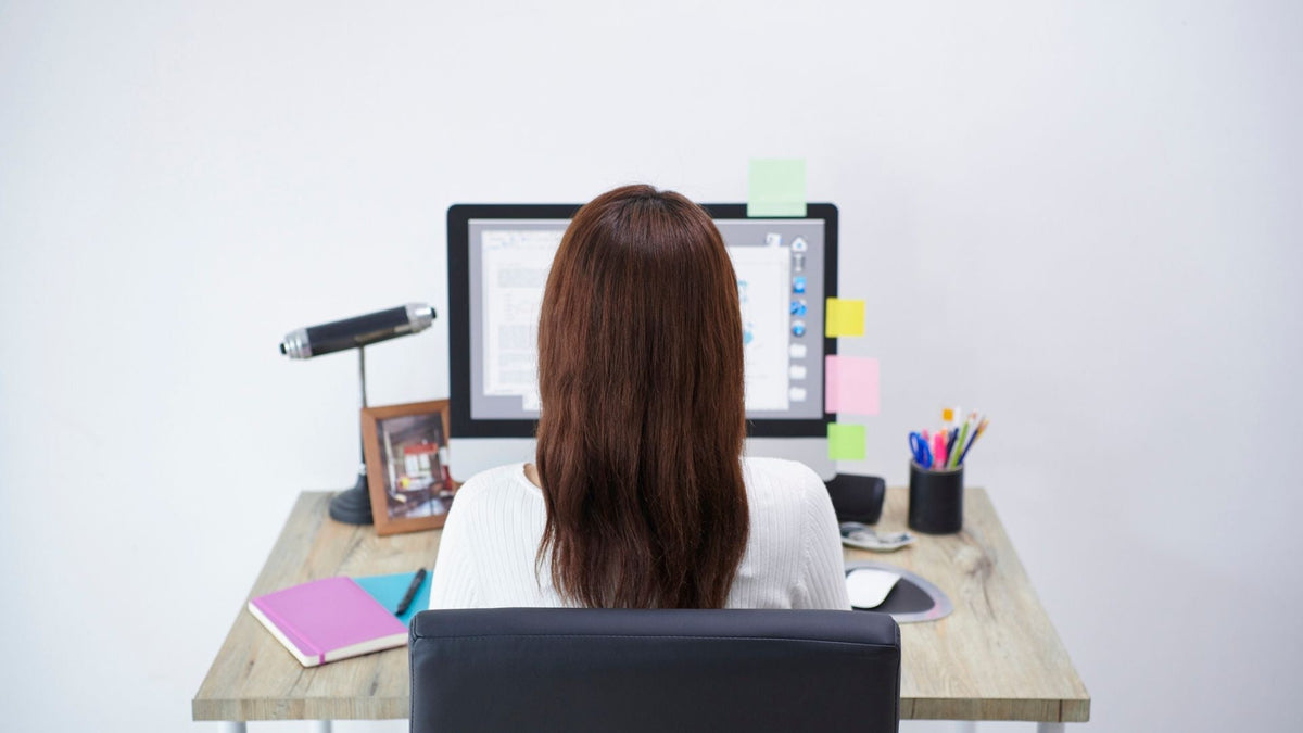 Person sitting at a desk with relaxed shoulders and straight posture, demonstrating proper shoulder posture while working at a computer.