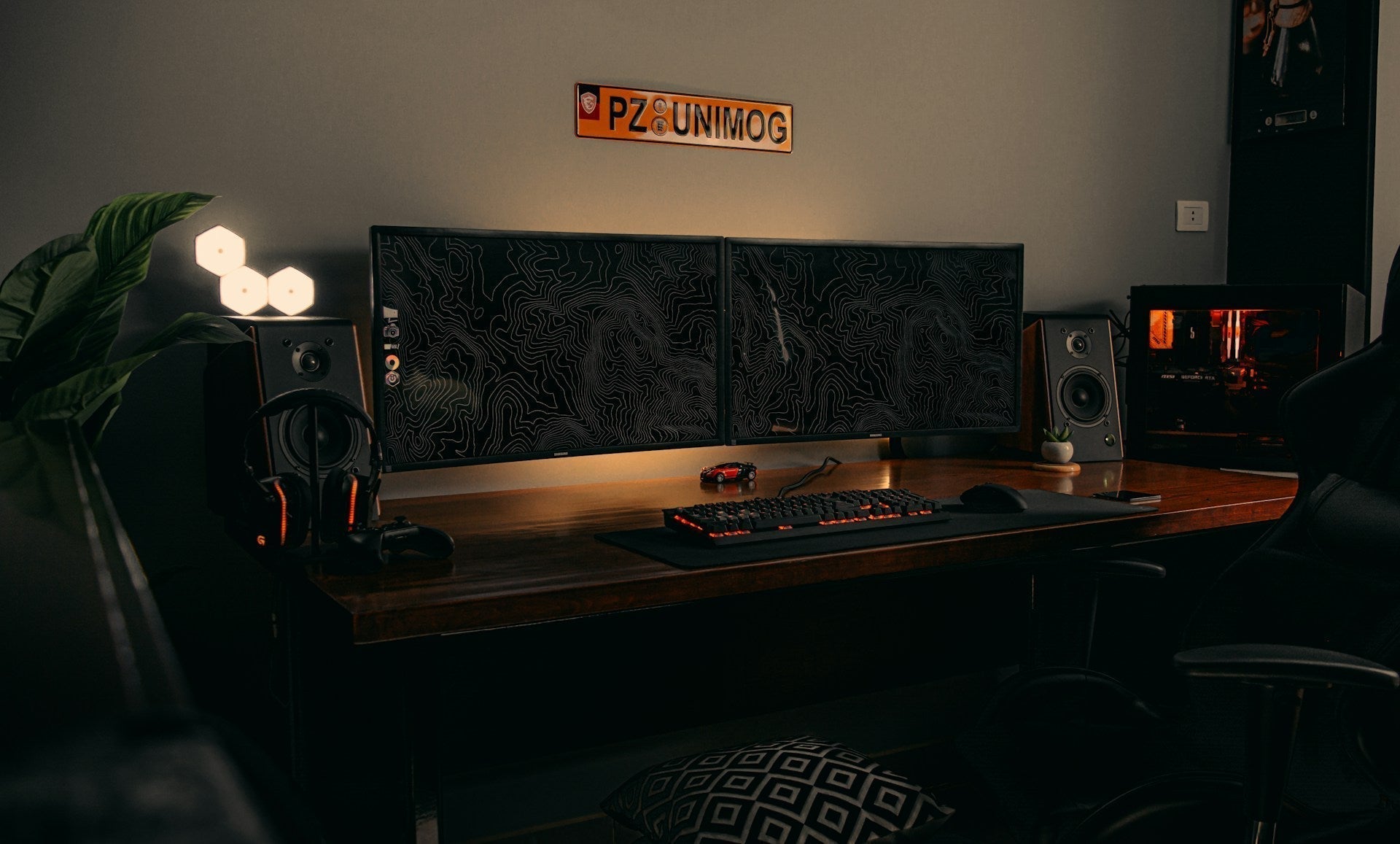 Modern corner gaming desk setup with dual monitors, speakers, gaming keyboard, and ambient lighting in a stylish home office