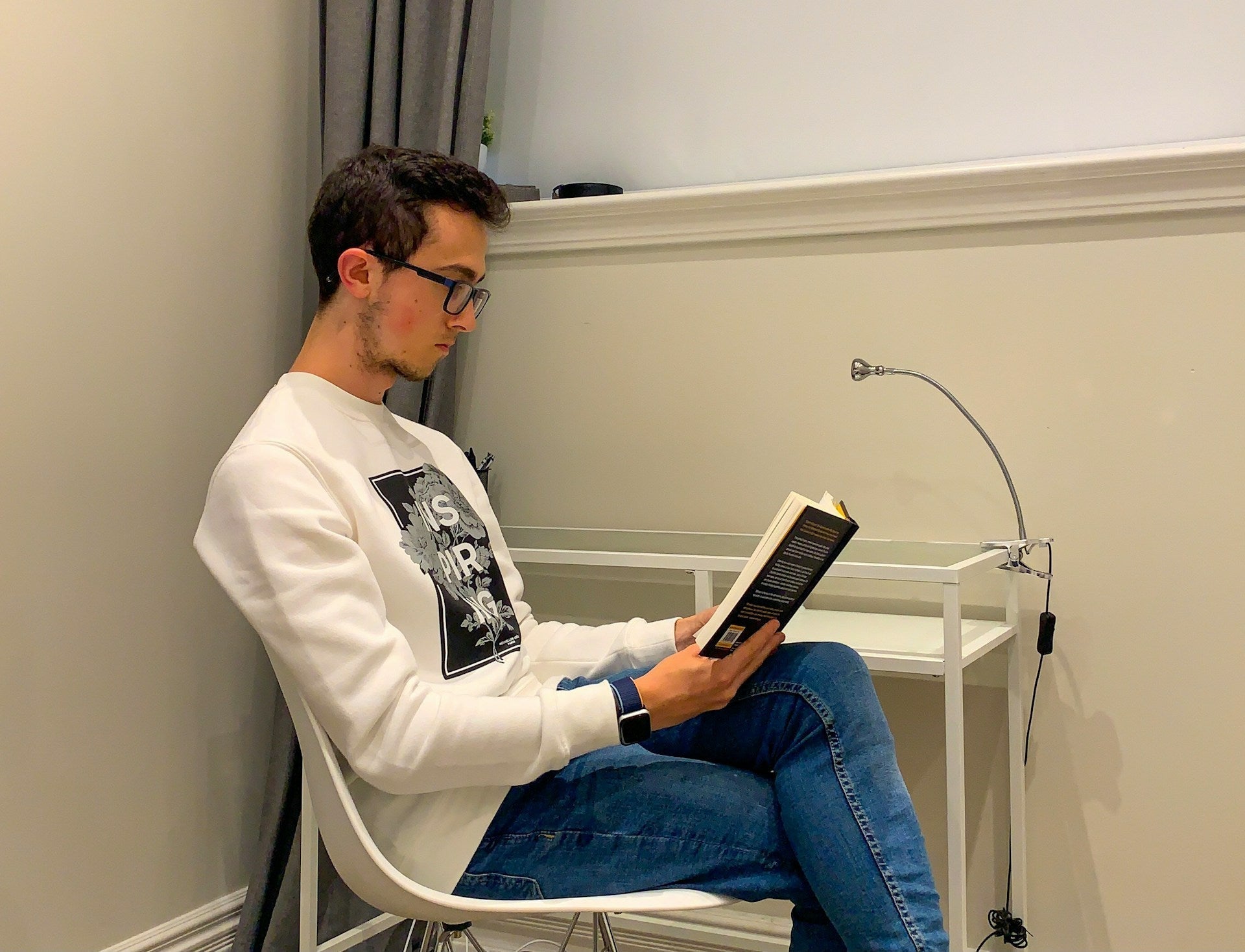 Does posture affect learning? A man reading a book in a corner sitting in a modern-looking chair. Image by Matt Lillywhite via www.unsplash.com