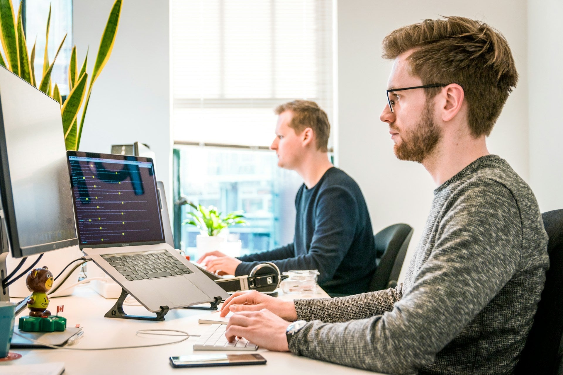 Two professionals working on computers in a bright office setup designed to enhance work productivity and focus. Photo by Tim van der Kuip on Unsplash