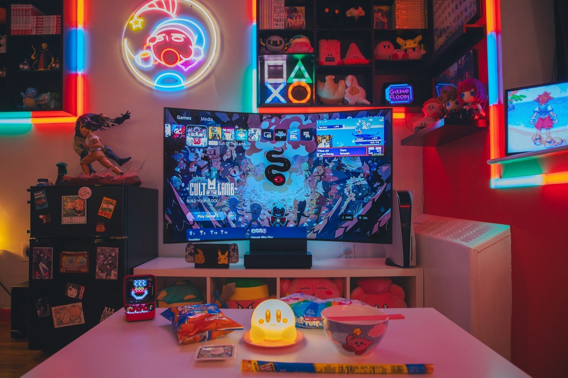 Colorful gaming room with LED lights, a large TV displaying a game, snacks on a table, and neon signs on the walls.