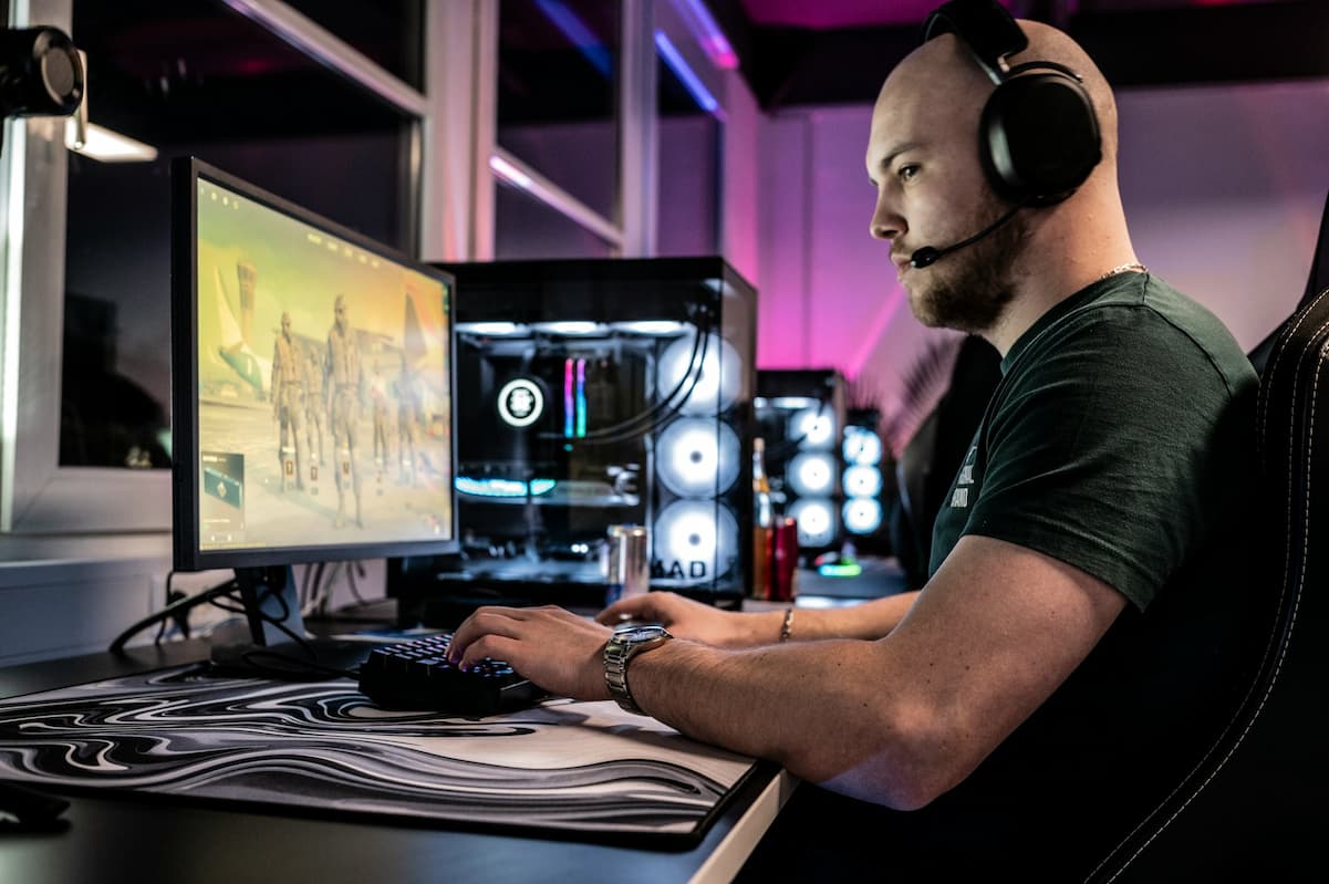 gaming room setup ideas. man playing a PC game in a well lit gaming room. photo by Ella Don via Unsplash
