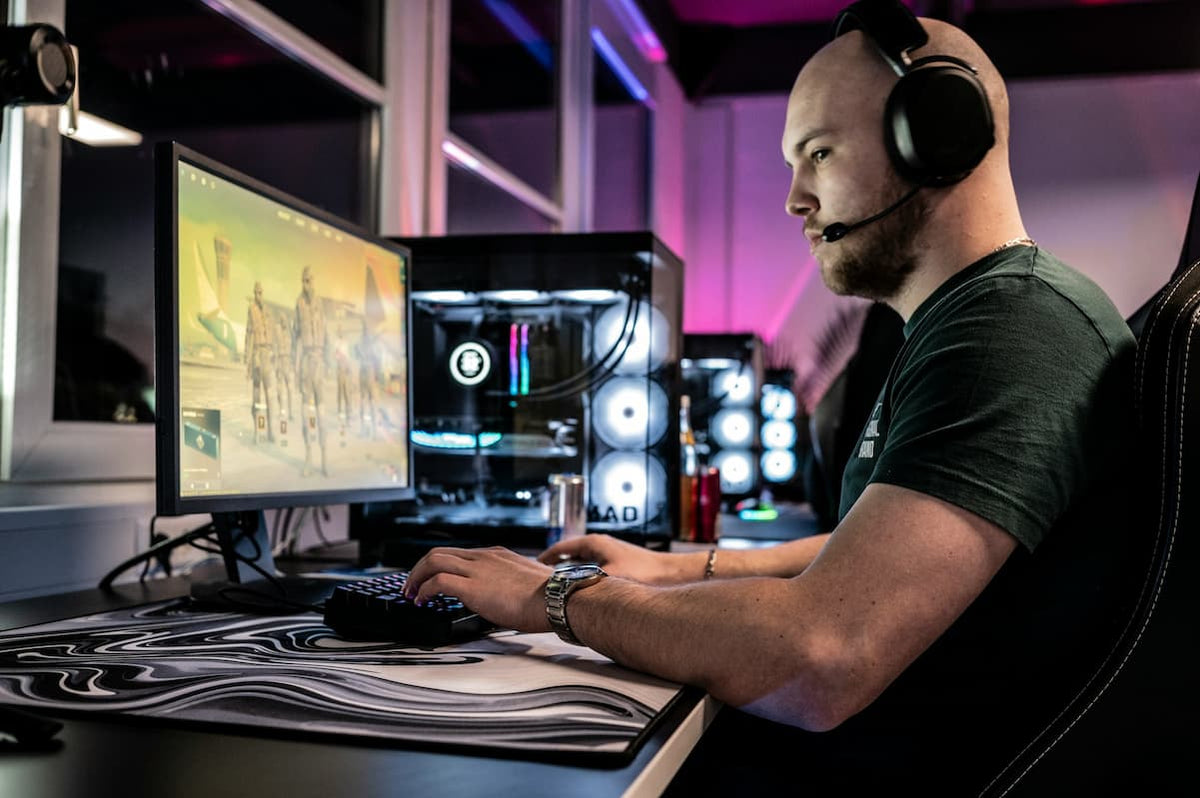 gaming room setup ideas. man playing a PC game in a well lit gaming room. photo by Ella Don via Unsplash