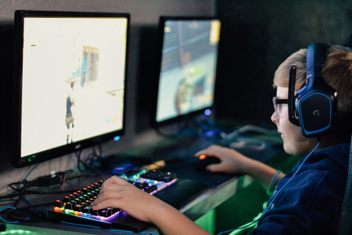 A young boy playing video games, very serious, makes you ask how gamers make money. Image by  Alex Haney via www.unsplash.com