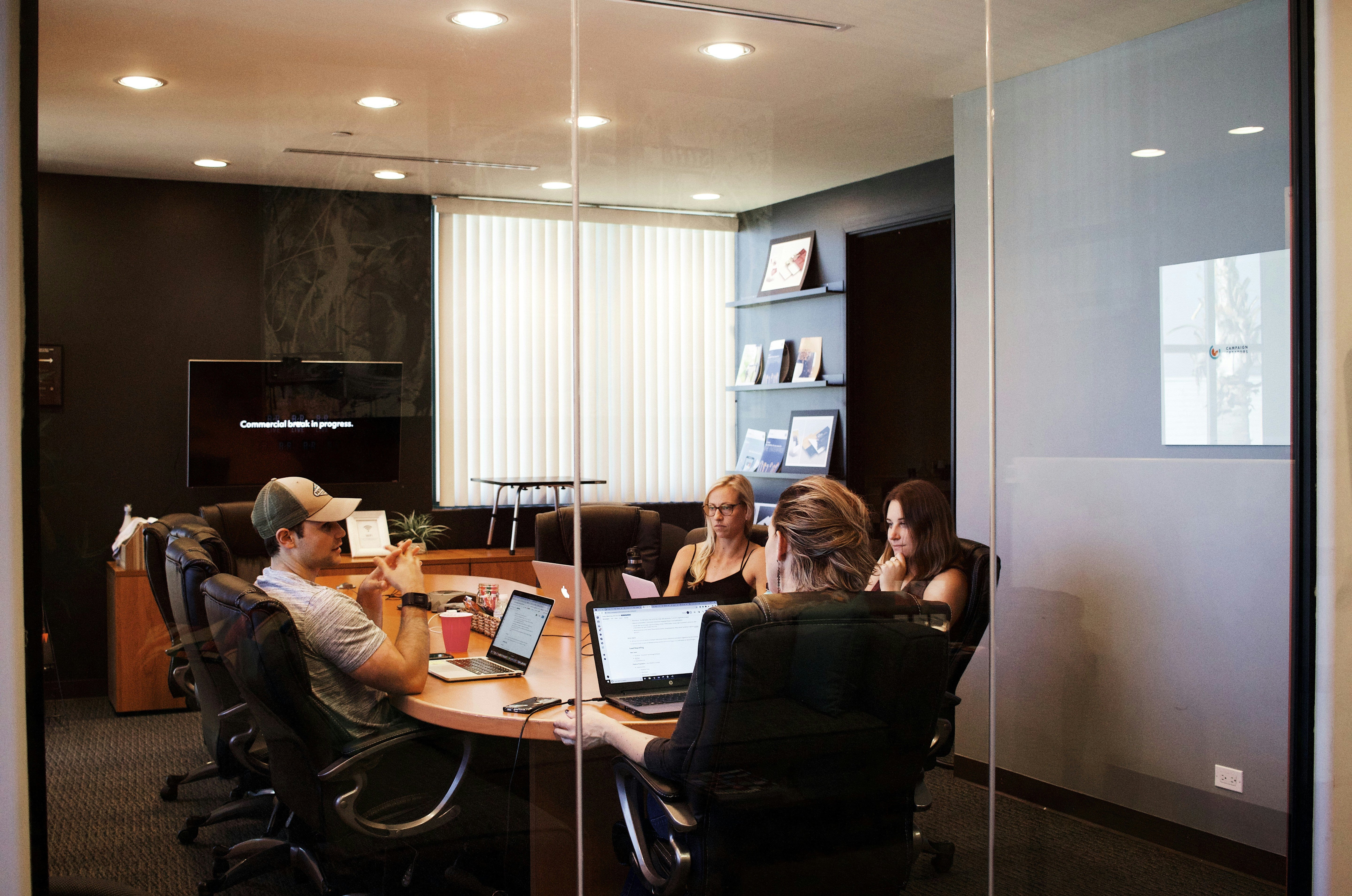 people sitting near table with laptop computer, talking about hybrid working arrangement. Image by Campaign Creators via www.unsplash.com