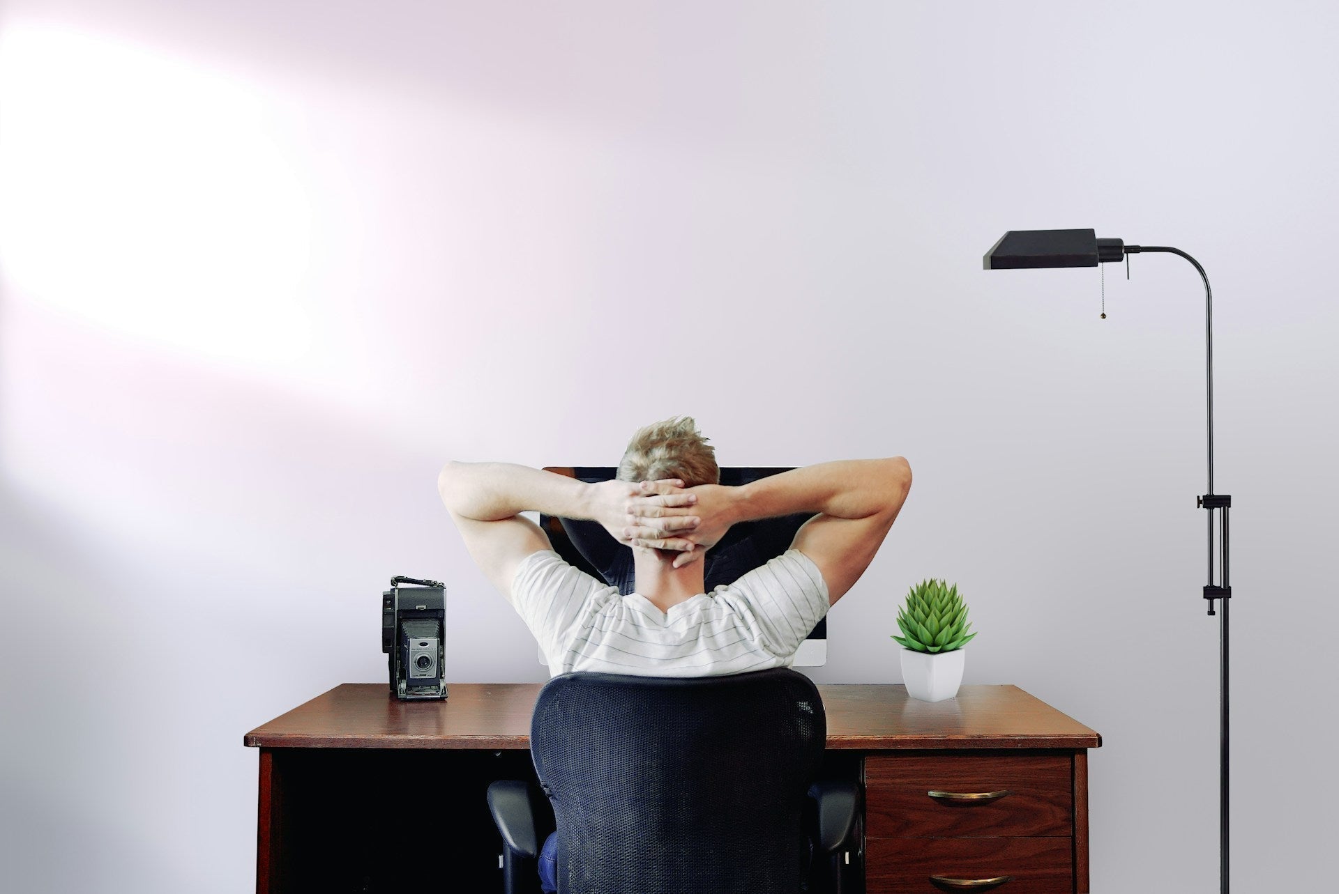 Man working contemplatively with good lighting in his home office with minimalist setting. Image by Jason Strull via www.unsplash.com