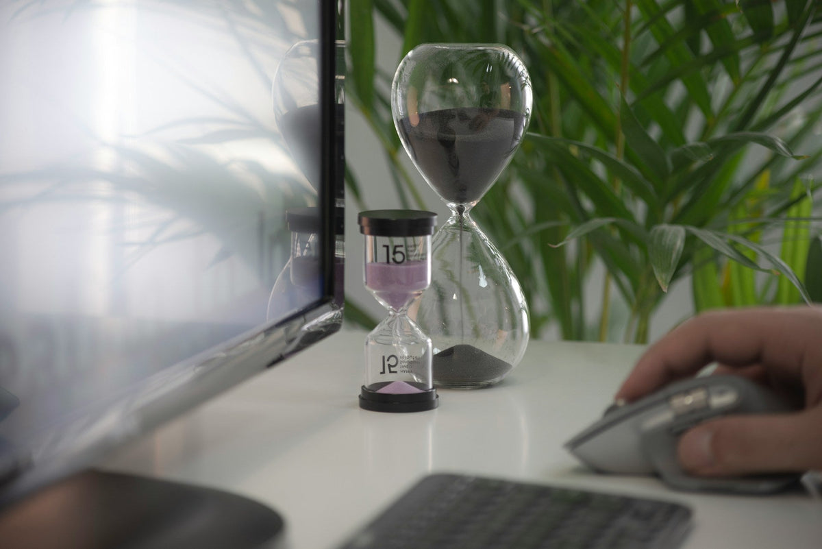 work success means time management. two hourglasses placed beside a monitor while a person is working the mouse. Image by Milad Fakurian via www.unsplash.com