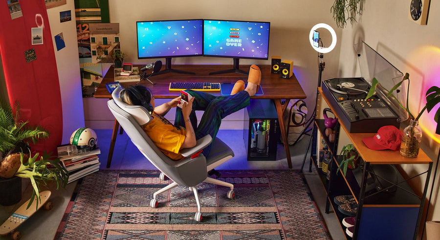 High-back ergonomic office chair in white and grey with adjustable armrests, caster wheels, and red highlight features with a boy seating and playing games,
