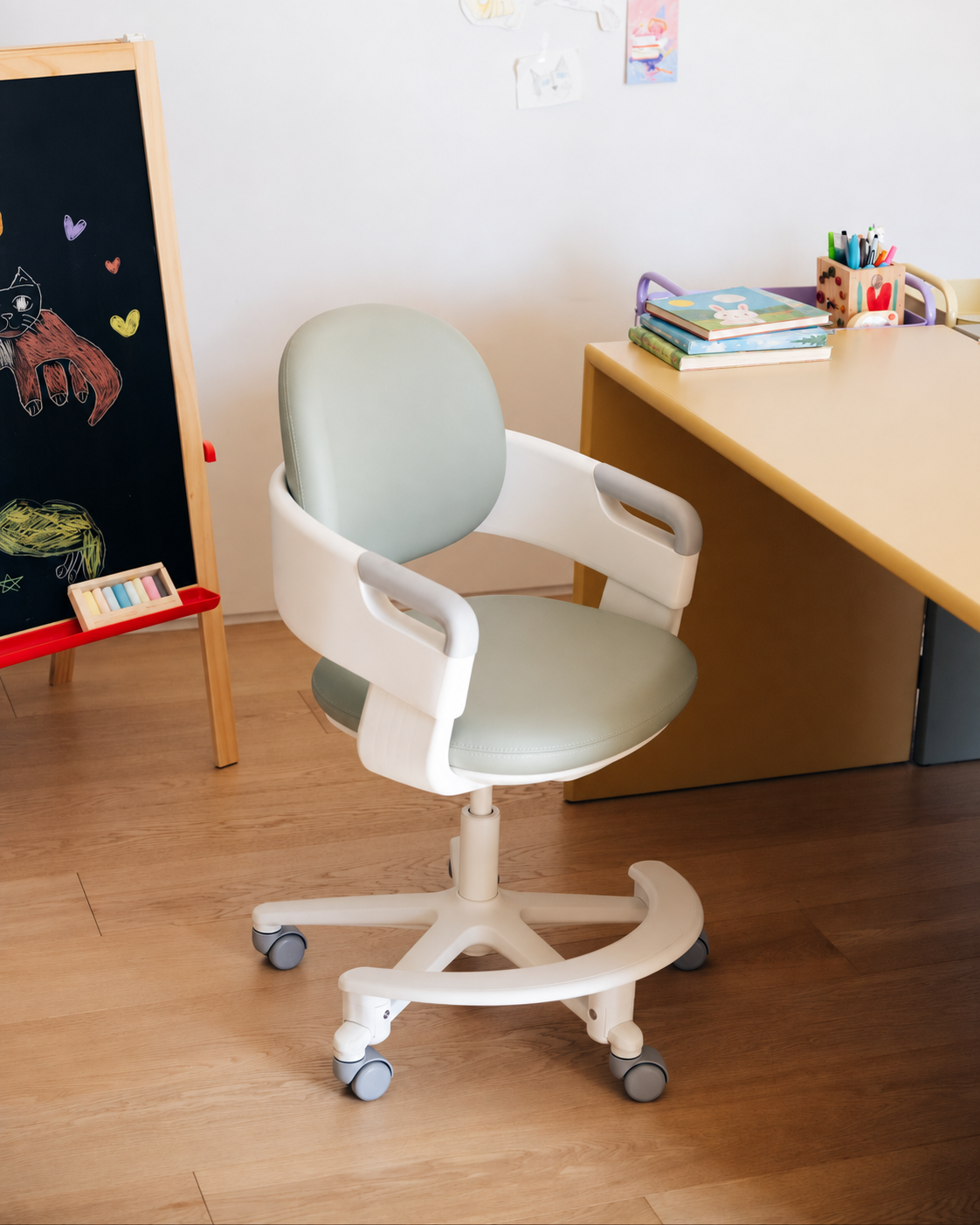 RINGO second-generation chair with rounded armrests and footrest beside a child's desk.